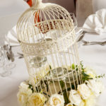 Close up of white bird cage with white flowers as table decoration