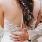 A groom places his hand gently on the back of his bride