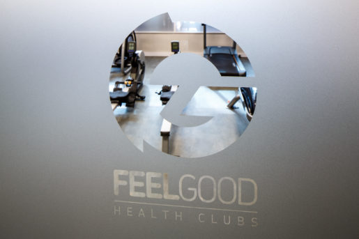 Feel Good Health Club branding on frosted glass door, showing gym equipment behind